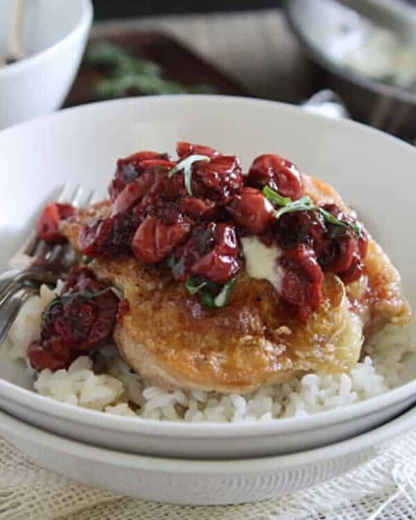 A bowl of rice with chicken and cherry sauce.