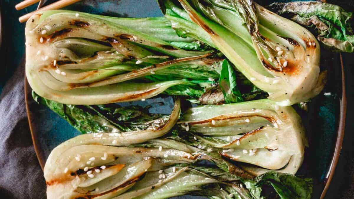 Grilled bok choy on a plate with chopsticks.