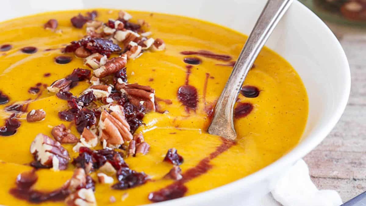 A bowl of kabocha squash soup with cherries and pecans.