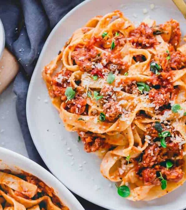 A plate of pasta with meat sauce and parmesan cheese.