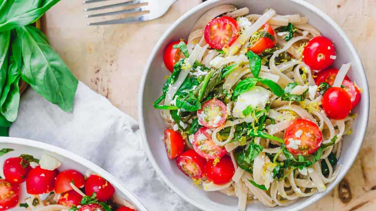Lemon pasta with spinach, feta and cherry tomatoes in a bowl.