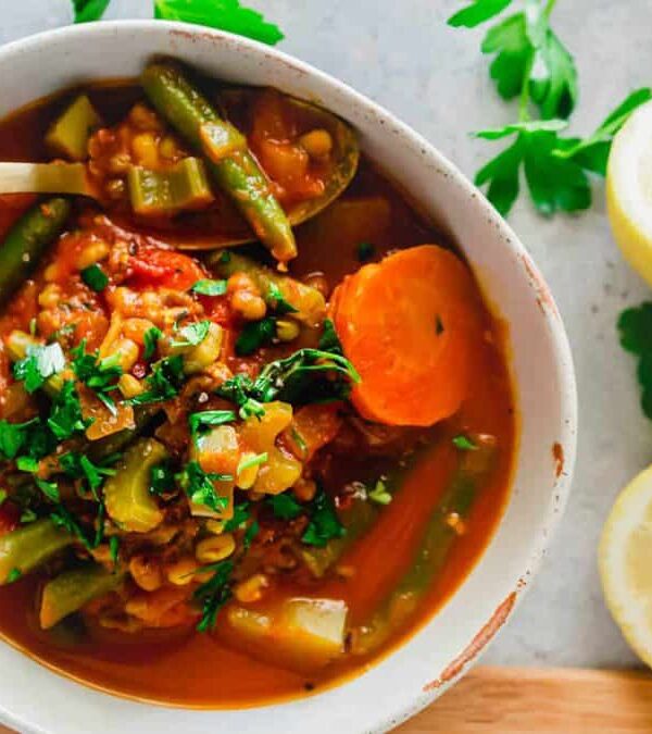 A bowl of mung bean soup with vegetables and lemons.