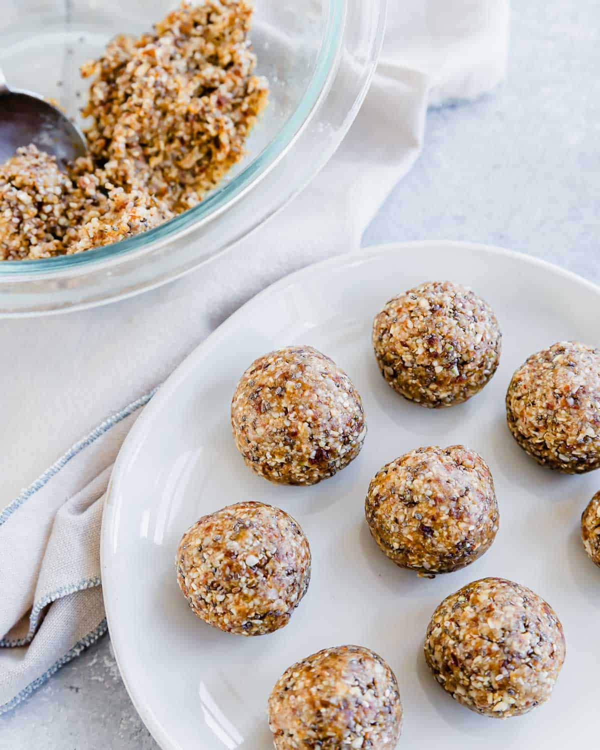A plate of almond oat and date balls and extra ingredients in a bowl in the background.