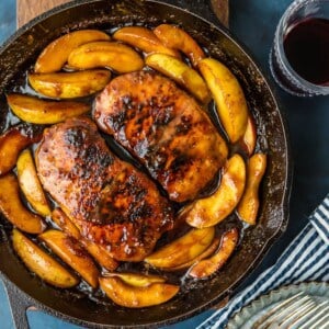 A cast iron skillet filled with apples and a glass of wine.