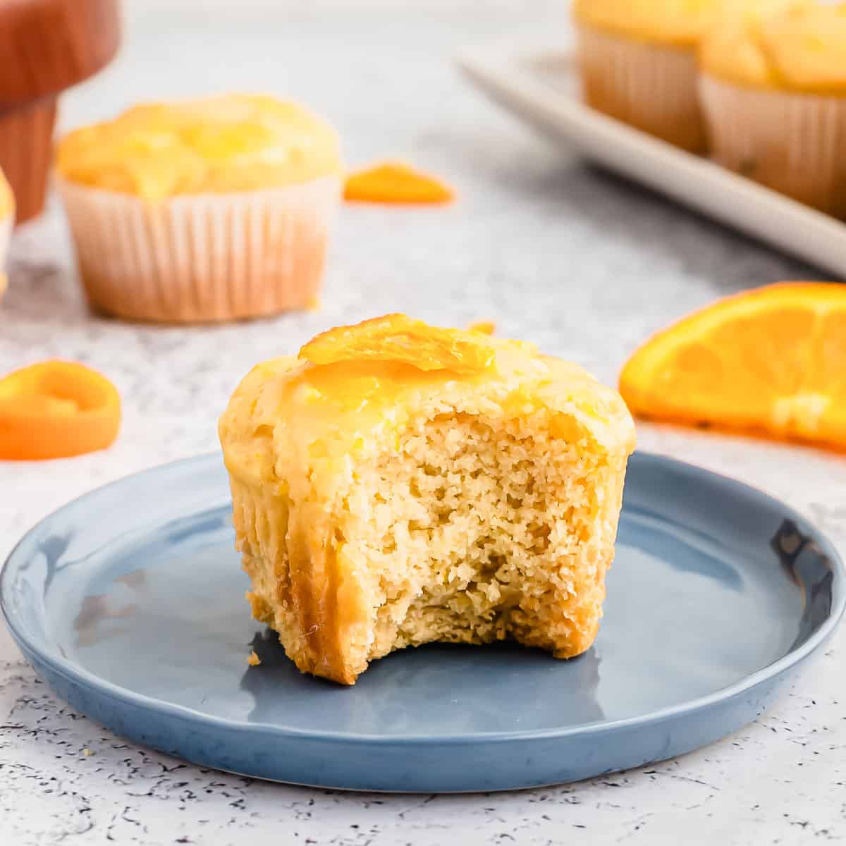 An orange muffin on a blue plate with a bite taken out of it.