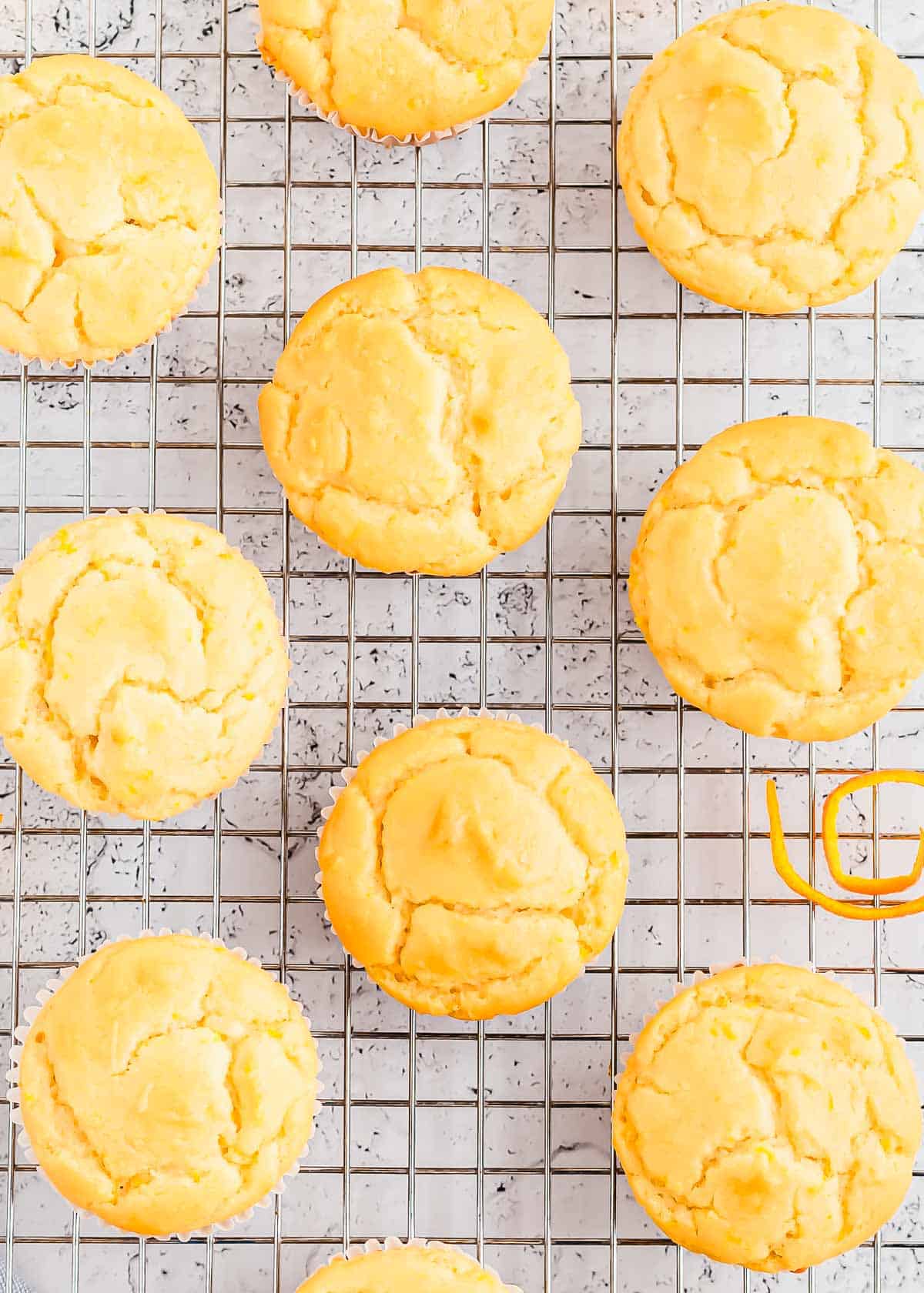 Orange muffins on a cooling rack with candied orange zest.