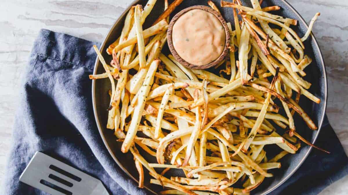 Parsnip fries on a plate with dipping sauce.
