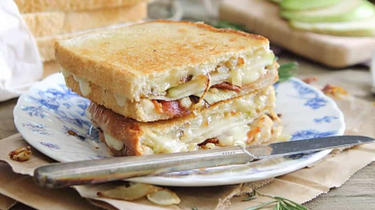 Pear bacon and brie grilled cheese on a plate with a knife.