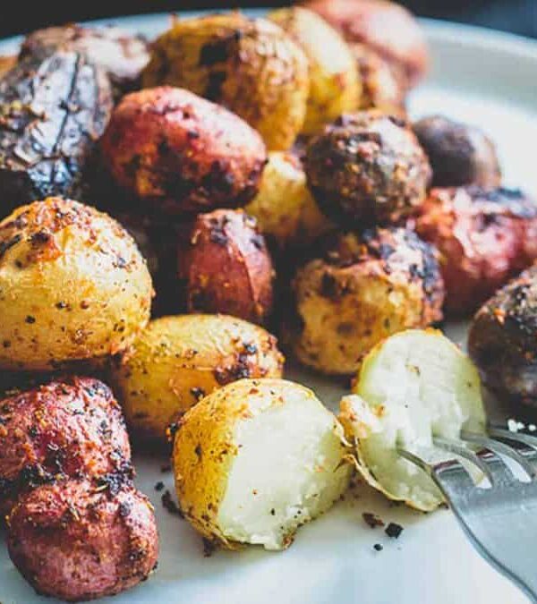 Roasted potatoes with peri peri seasoning on a plate with a fork.