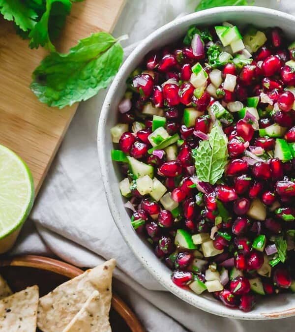 A bowl of pomegranate salsa with lime and tortilla chips.