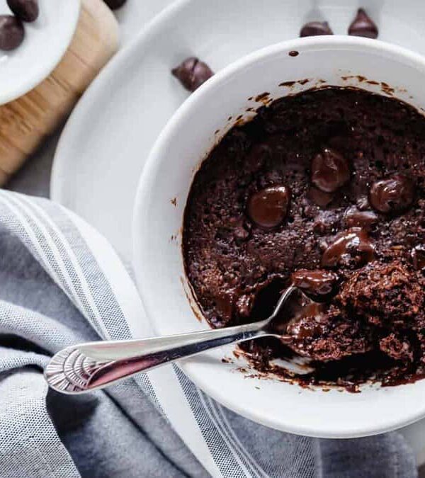 Chocolate cake in a white bowl with a spoon.