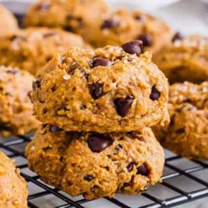 A stack of pumpkin chocolate chip cookies on a cooling rack.