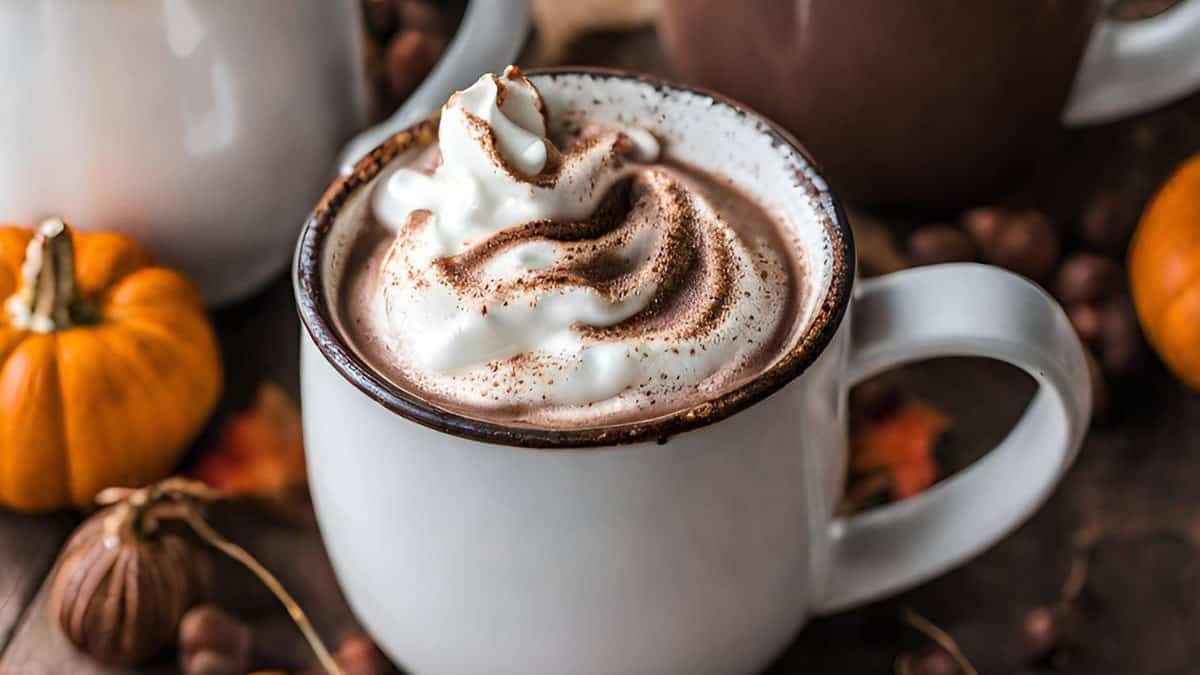 A cup of hot chocolate with whipped cream and pumpkins.
