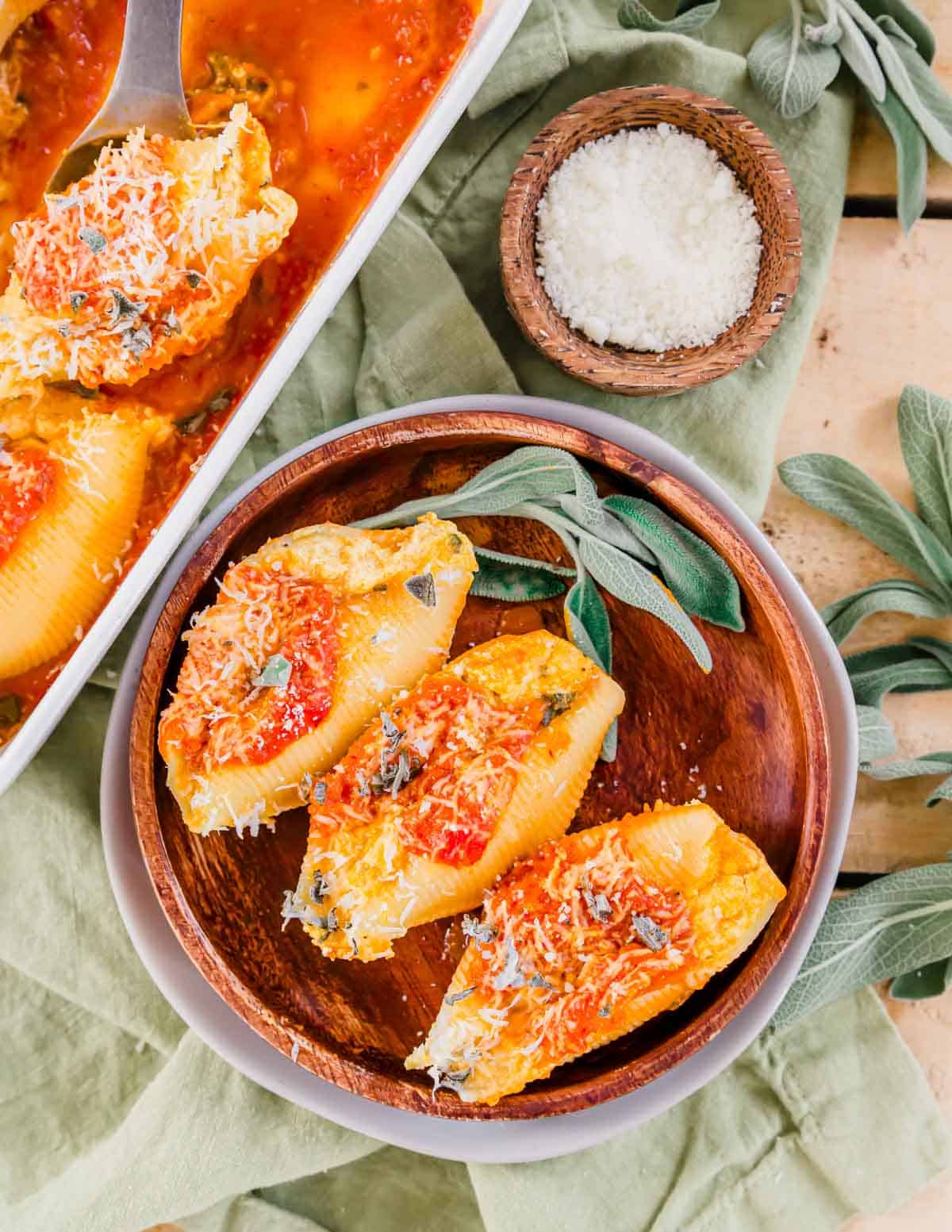 Ricotta stuffed shells on a wooden plate with fresh sage.