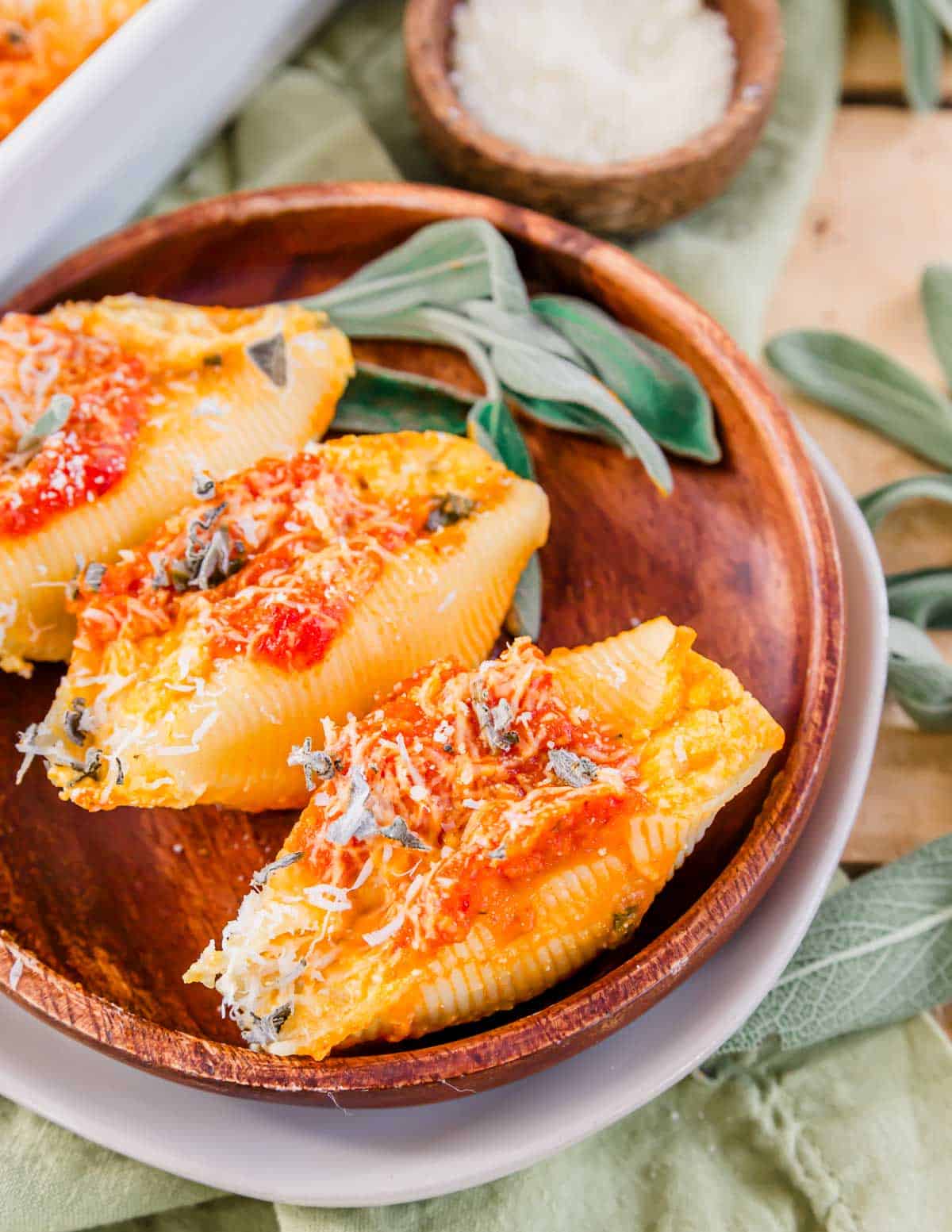 Stuffed shells with pumpkin on a wooden plate with fresh sage.