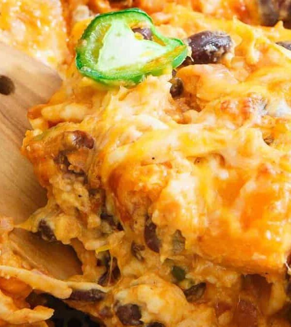 Mexican casserole in a casserole dish with a wooden spoon.