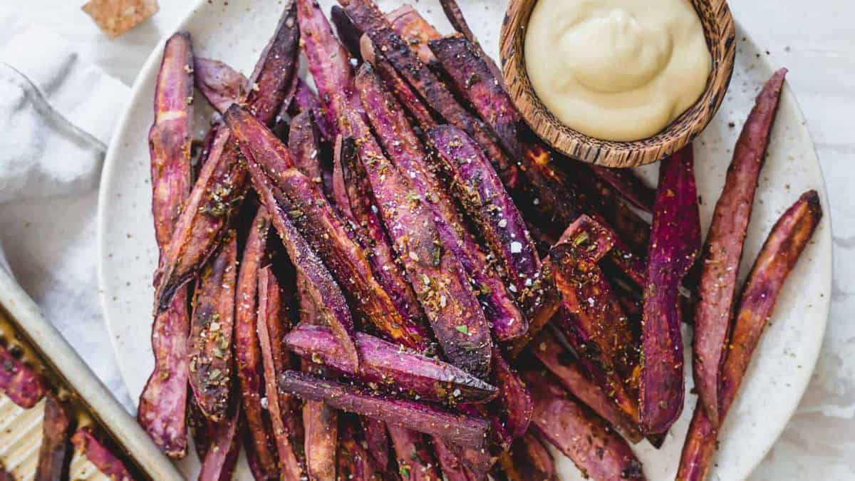 Purple sweet potato fries on a plate with dipping sauce.