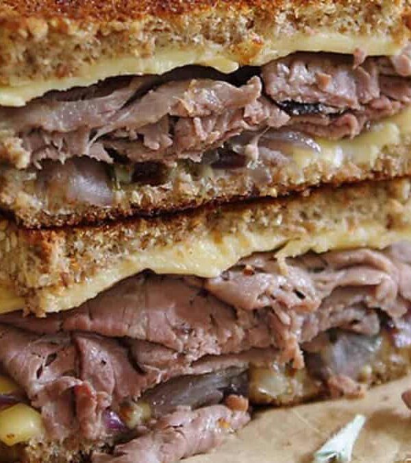 A grilled sandwich with meat and cheese on top.