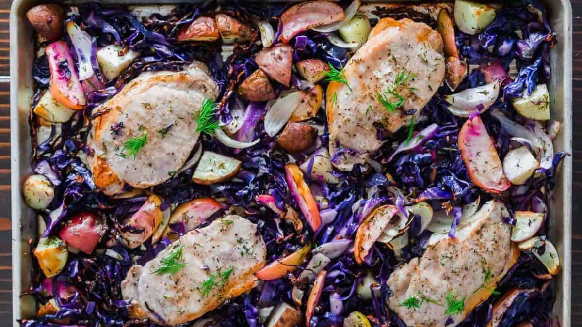 Red cabbage and pork chops with potatoes in a baking pan.