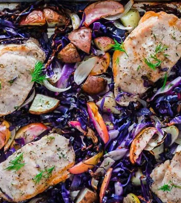 Red cabbage and pork chops with potatoes in a baking pan.