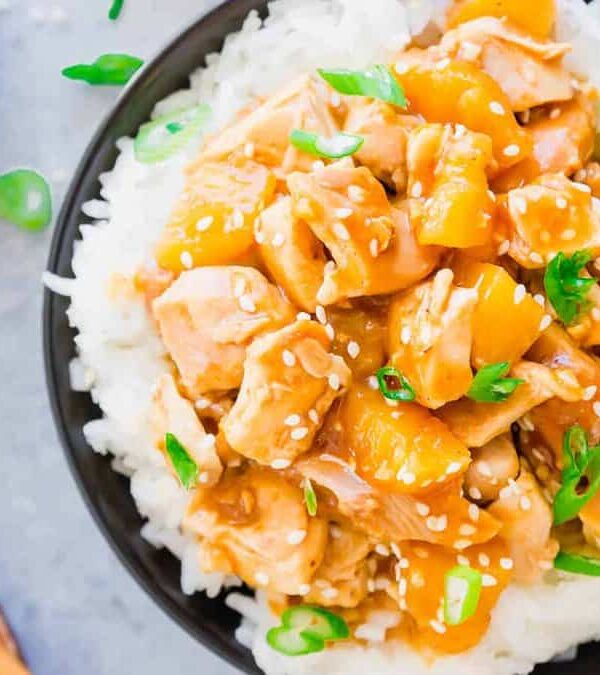 A bowl of asian chicken and rice with chopsticks.
