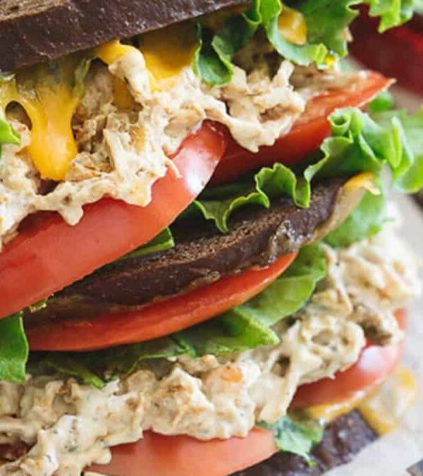A sandwich with chicken salad, tomatoes and lettuce.
