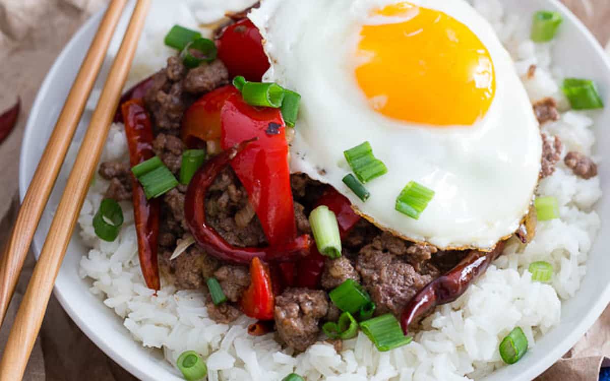 Spicy beef and red pepper rice bowl topped with a fried egg over white rice.