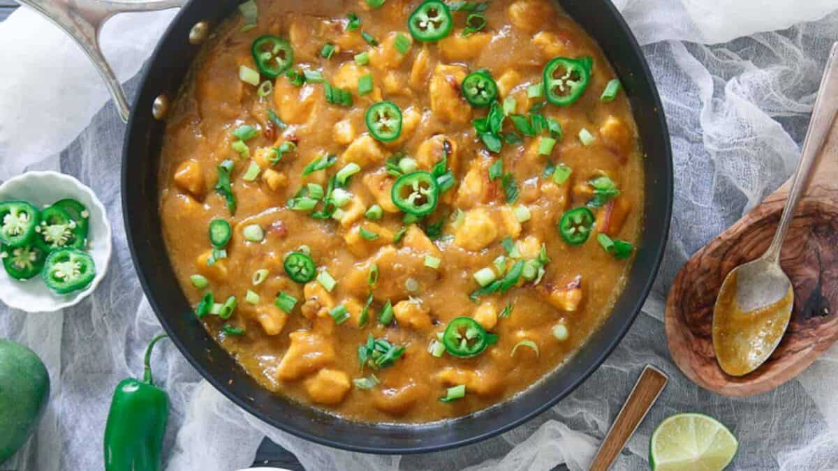 A skillet full of chicken in a mango sauce.