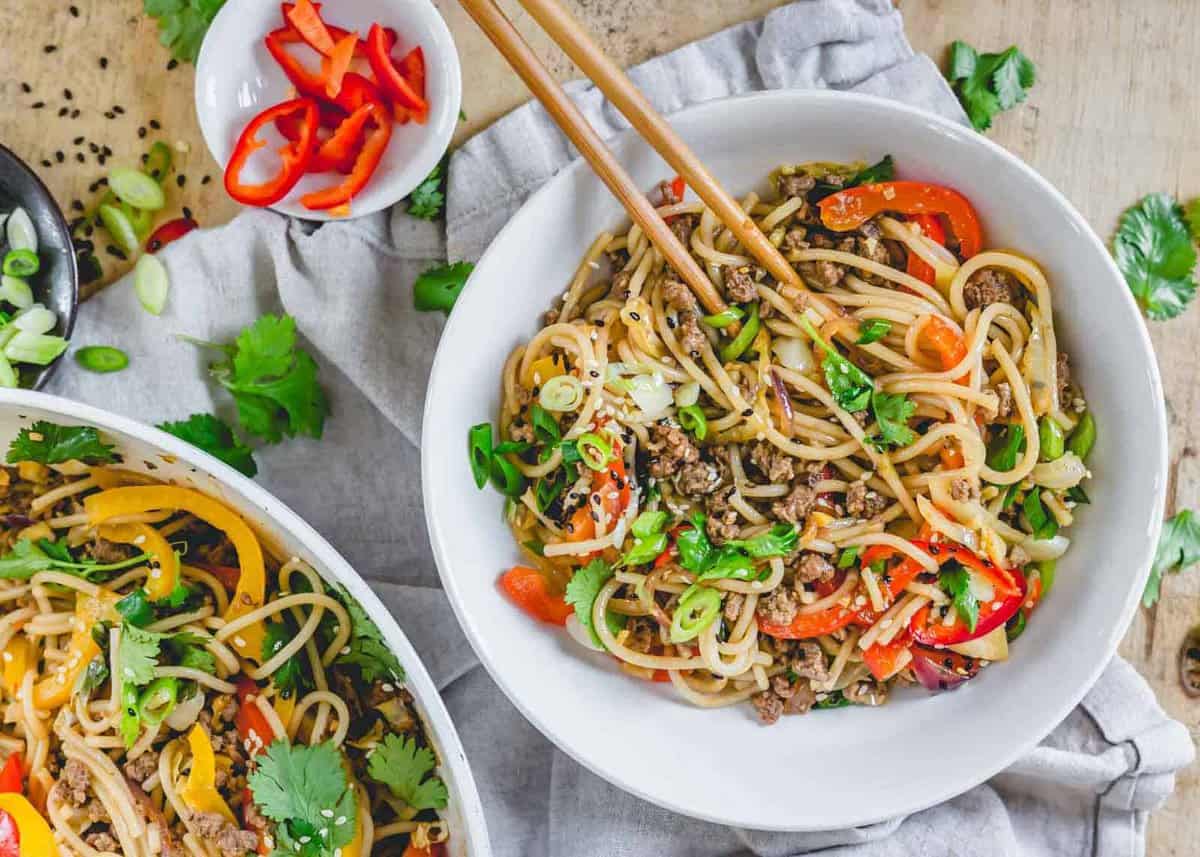 Spicy udon noodle stir fry in a bowl with chopsticks.