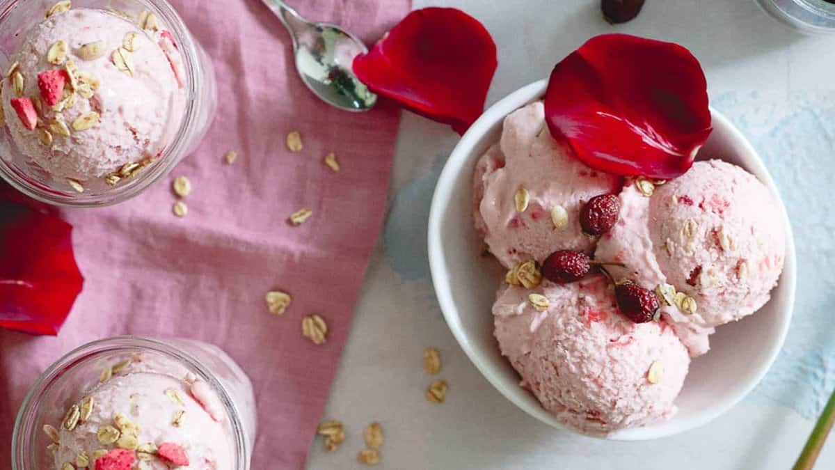 Strawberry granola ice cream in a white bowl with a red rose leaf.
