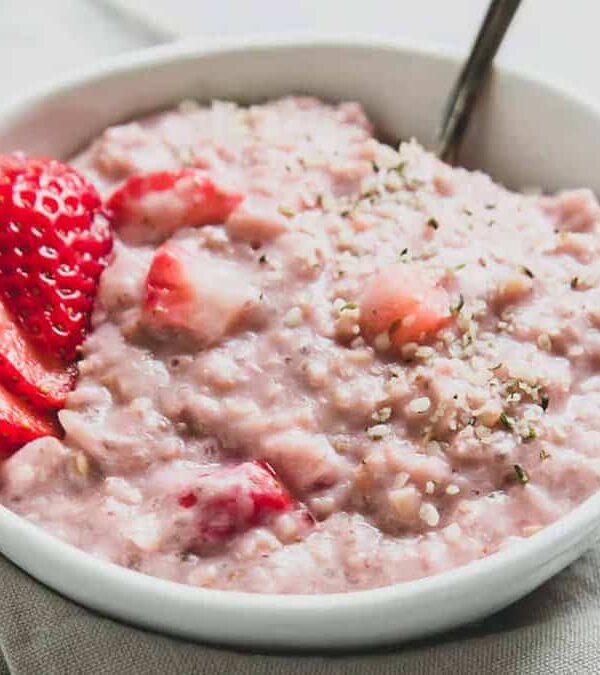 Strawberry oats in a white bowl with a spoon.