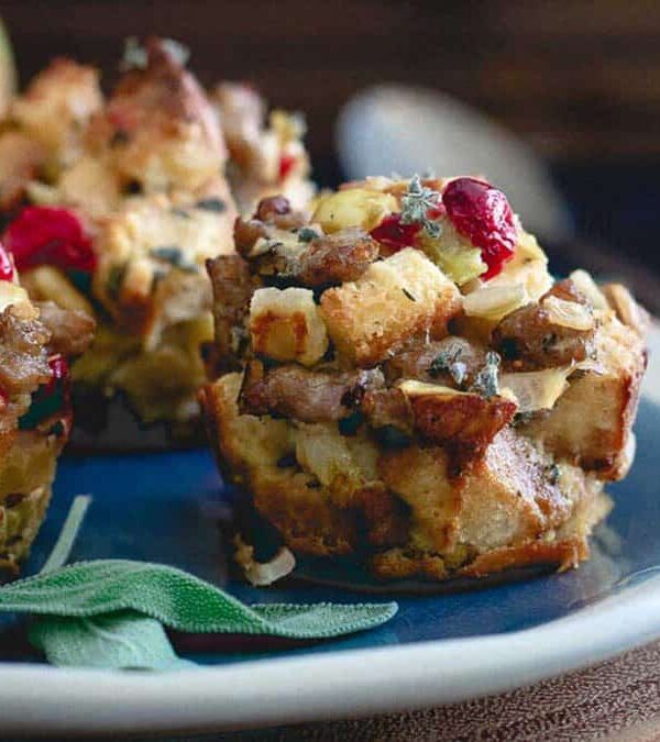 Stuffing muffins on a plate with apples and sage.