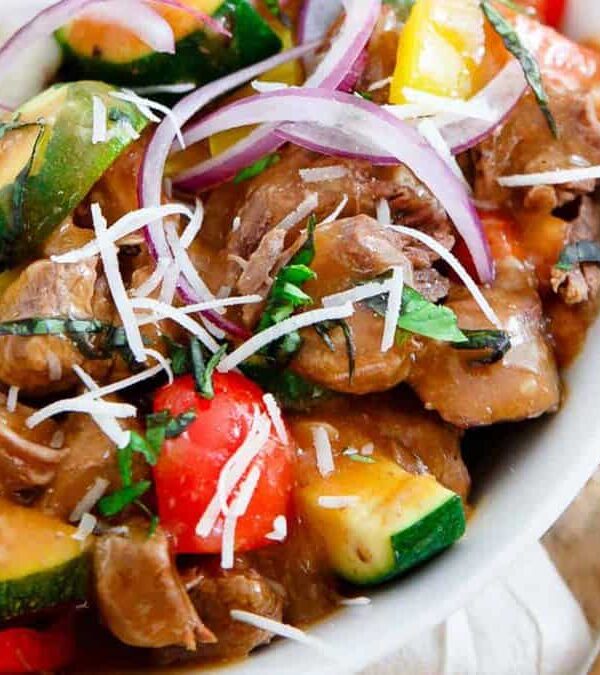 A bowl of beef stew with vegetables and mashed potatoes.