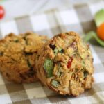 Two tomato leek muffins sitting on a checkered napkin.