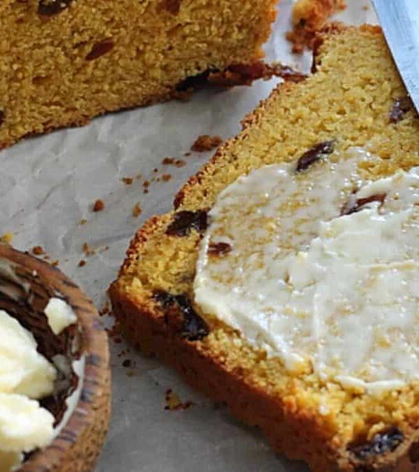 A slice ofs weet potato bread with butter and raisins on it.