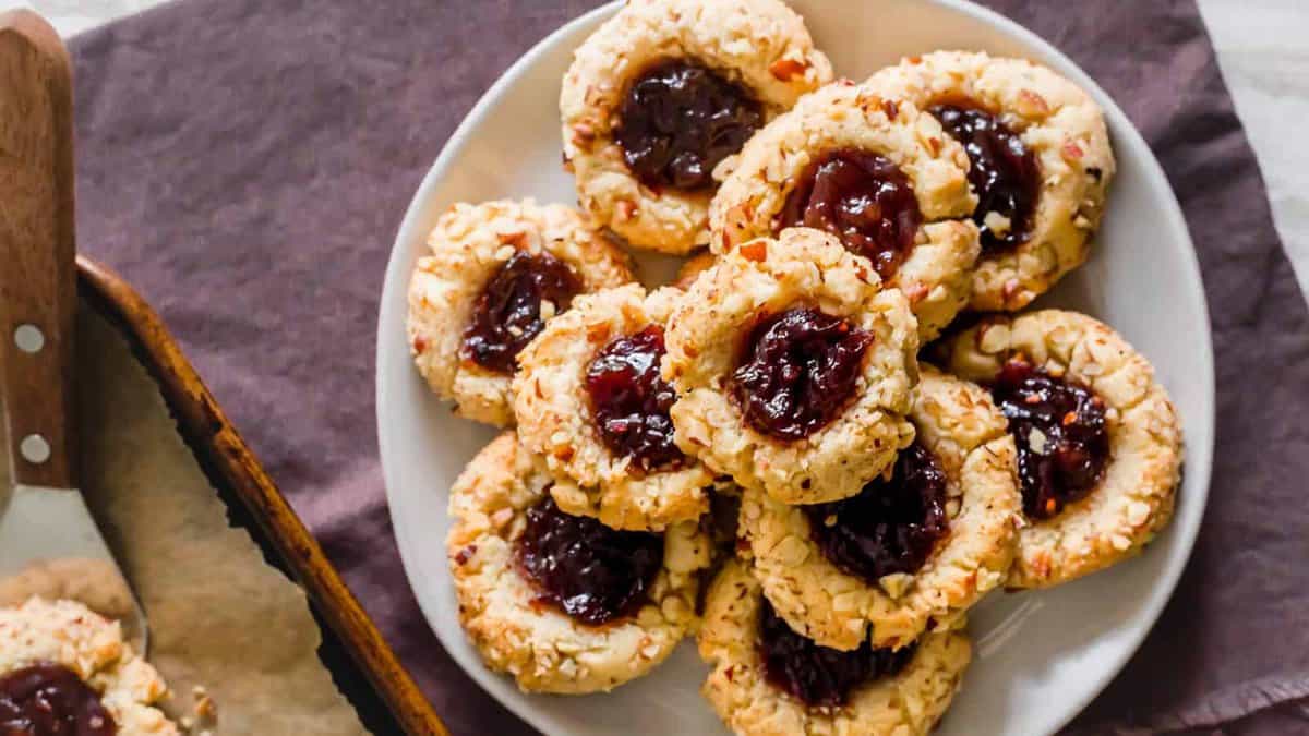 A plate of cookies with jam and nuts on it.