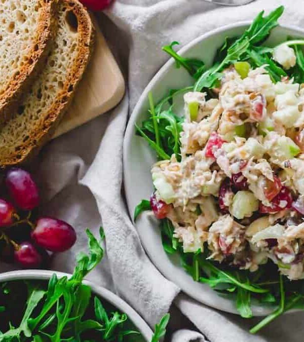 A bowl of tuna salad with grapes and bread.