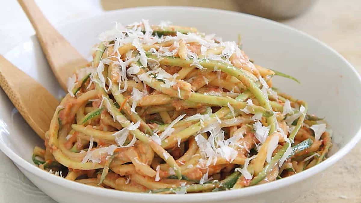 Zucchini noodles with creamy tomato sauce and parmesan cheese in a white bowl.