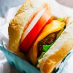 Turkey burger with fixings wrapped in parchment paper.