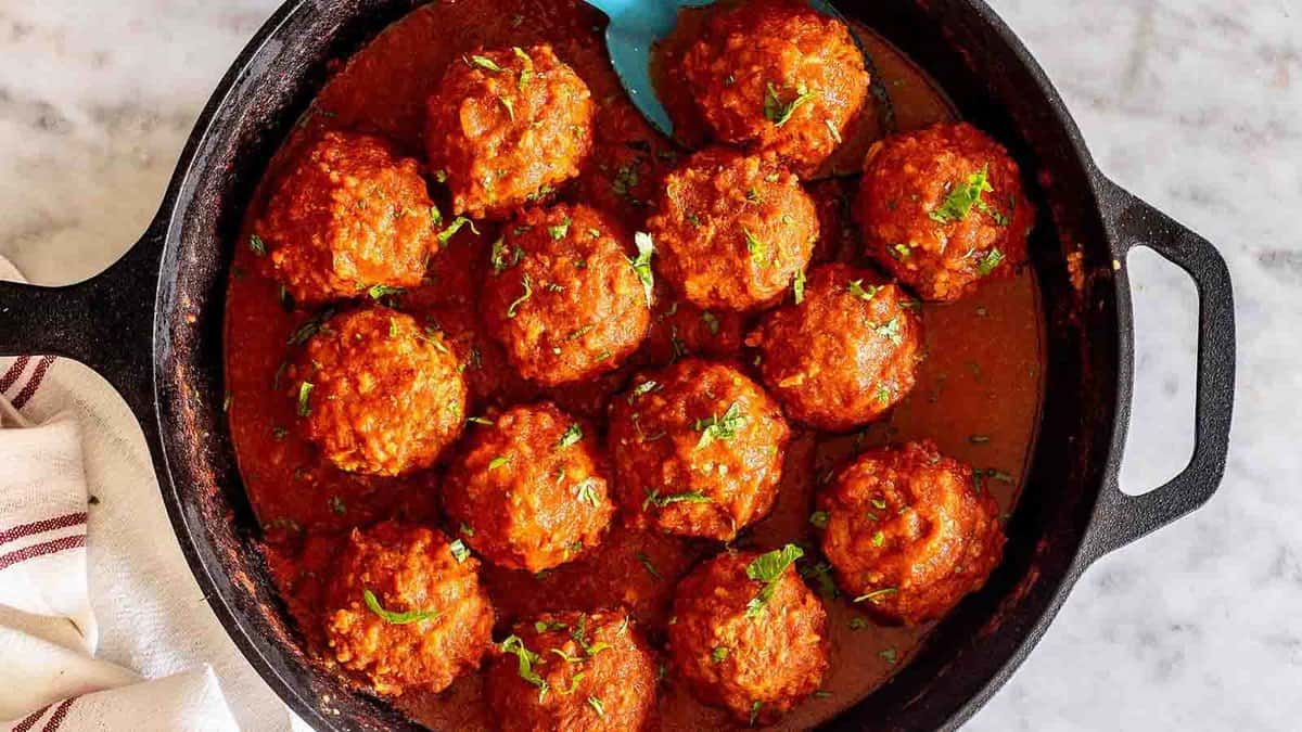 A skillet filled with meatballs in a tomato sauce.