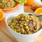Bulgur salad in a white bowl with orange dressing.