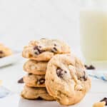 Macadamia nut chocolate chip cookies stacked on a white surface.