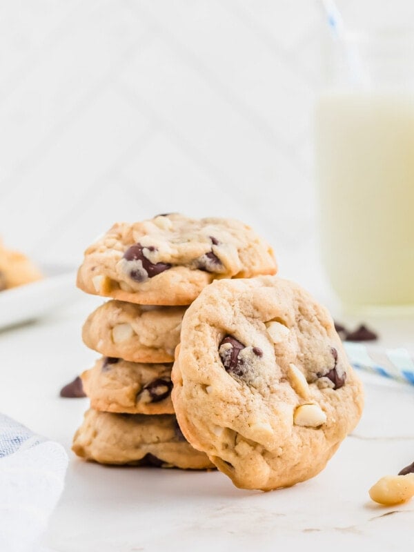 Macadamia nut chocolate chip cookies stacked on a white surface.