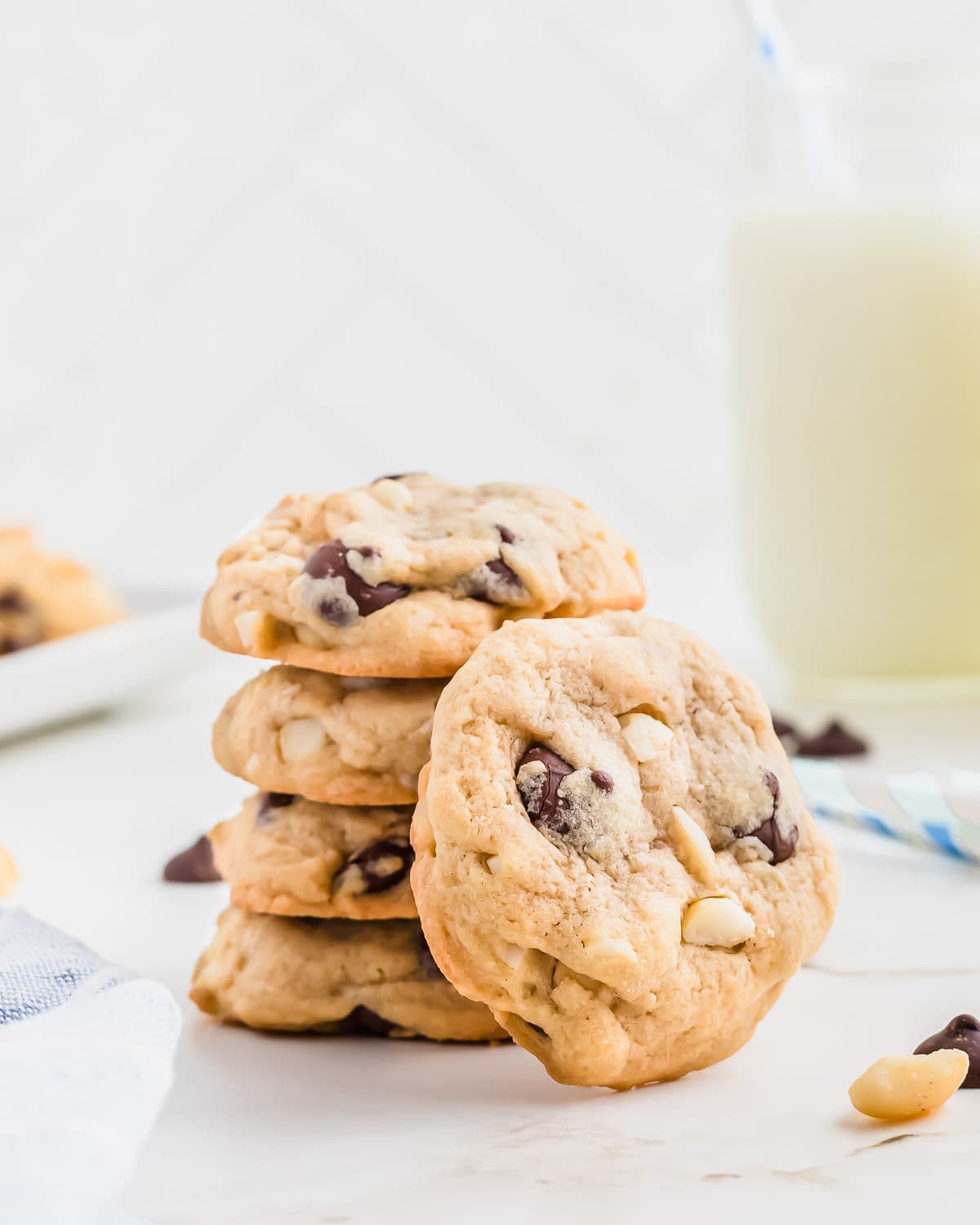 Macadamia nut chocolate chip cookies stacked on a white surface.