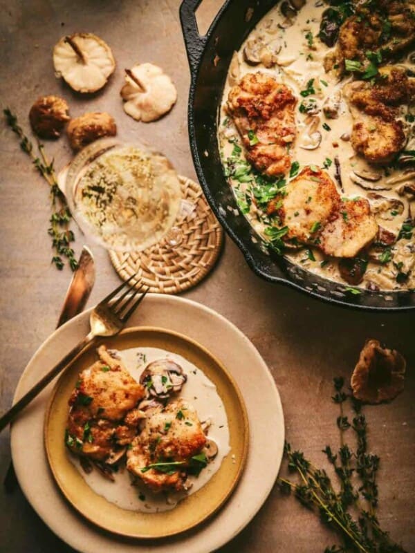 Champagne chicken plated with a fork and a skillet behind it.