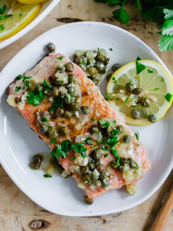 Salmon piccata on a plate with a fork on the side.