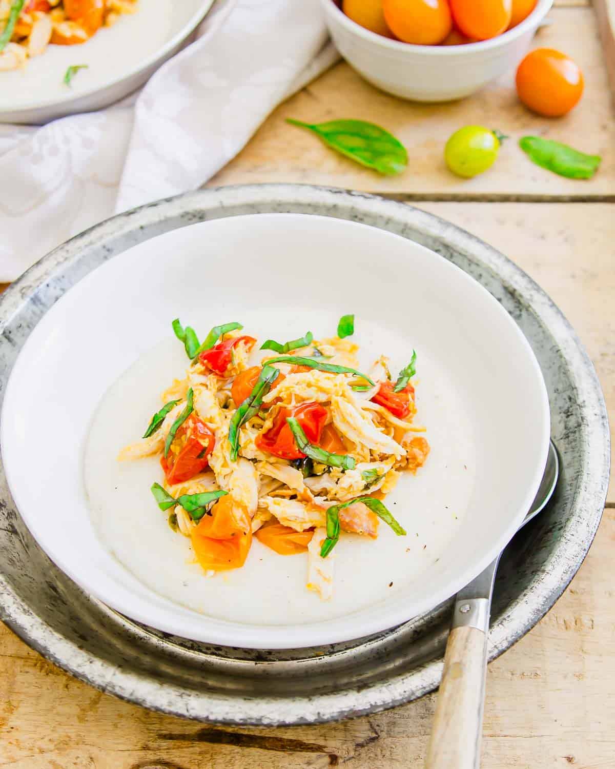 Creamy goat cheese grits with shredded chicken, basil and cherry tomatoes.