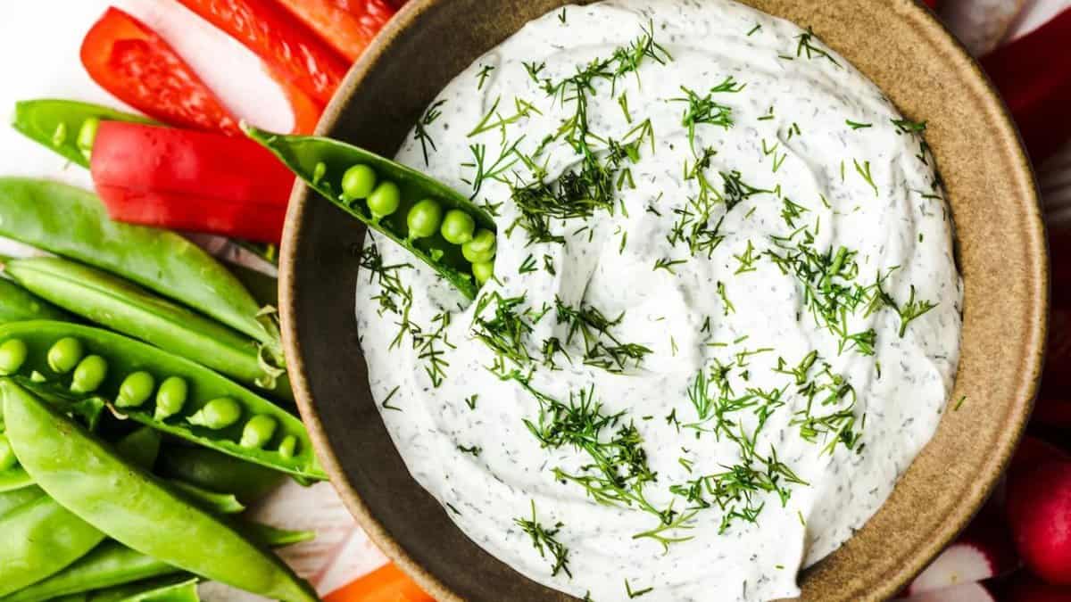 Greek yogurt dip with dill in a bowl and fresh vegetables.
