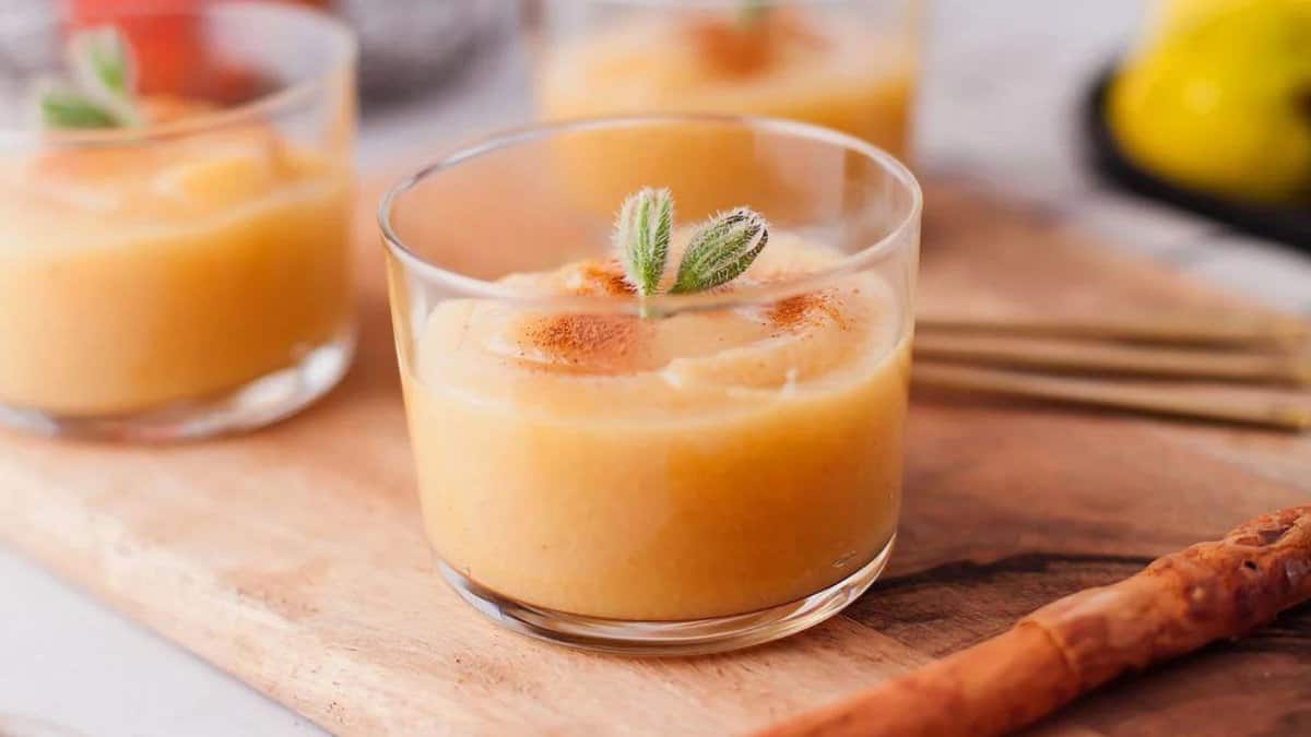 Guava applesauce in a glass cup garnished with cinnamon and herbs.