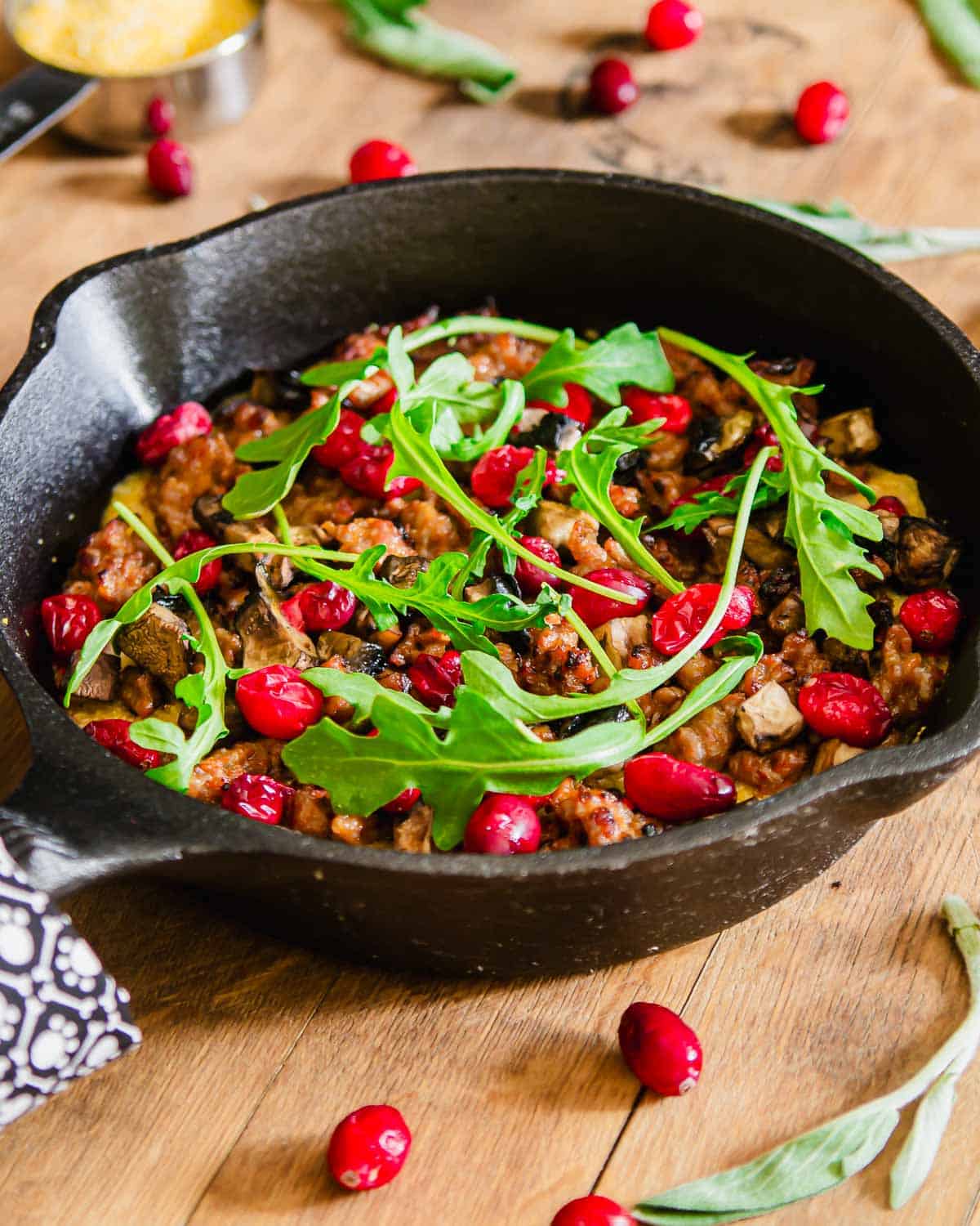 Skillet cheddar polenta and sausage topped with cranberries and arugula.